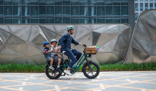 Un hombre está montando una bicicleta eléctrica Fiido T2 con dos niños.