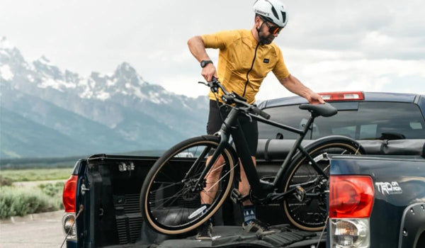 Un hombre está colocando una bicicleta eléctrica Fiido C21 en la caja de un camión.