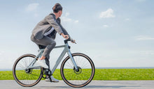 Un hombre conduce una bicicleta eléctrica Fiido Air a toda velocidad por la carretera.