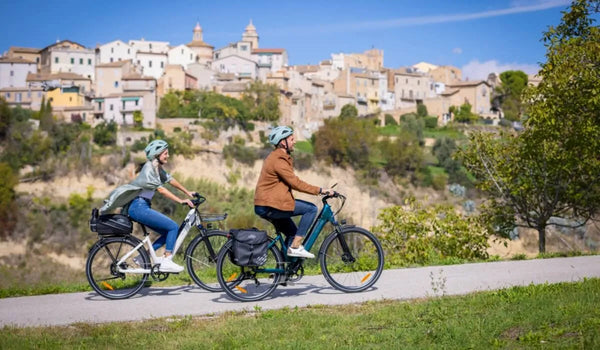 Un hombre y una mujer suben cuesta arriba en bicicletas eléctricas Fiido C11.