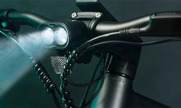 Ciclista viajando en una e-bike Fiido en la oscuridad y encendiendo el faro de la e-bike.