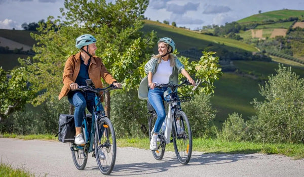 Un hombre y una mujer viajando en bicicletas eléctricas Fiido C11 en la carretera.