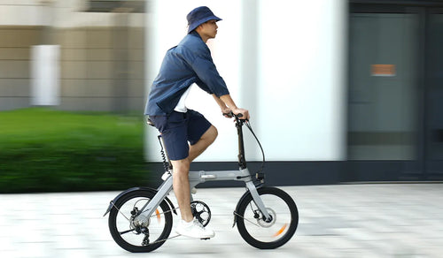 Un hombre conduce una bicicleta eléctrica Fiido D11 por una calle urbana.