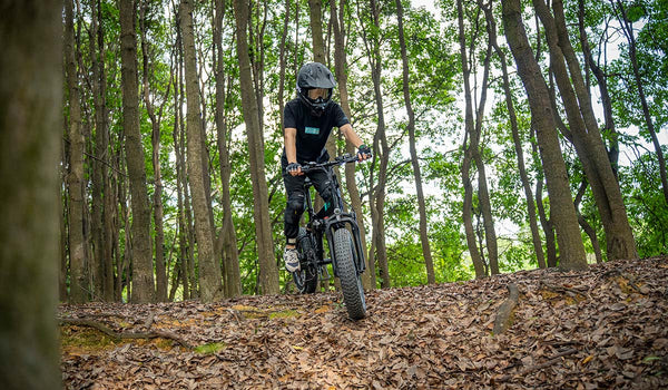 Hombre montando bicicleta eléctrica Fiido M1 Pro en el bosque.