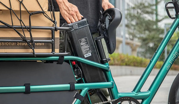 Un hombre se prepara para hacerle mantenimiento a la batería de una bicicleta eléctrica Fiido T2.