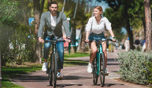 Una pareja monta bicicletas eléctricas Fiido C21 por un parque.