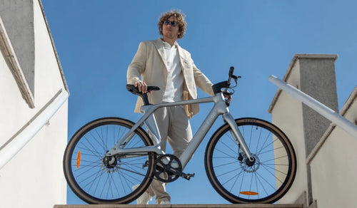 Un hombre monta una bicicleta eléctrica Fiido Air de fibra de carbono por la ciudad.