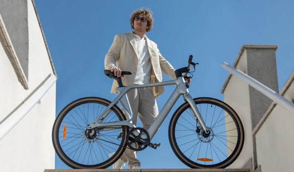 Un hombre monta una bicicleta eléctrica Fiido Air de fibra de carbono por la ciudad.
