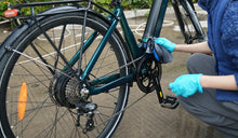 Una mujer limpia el cuadro de una bicicleta eléctrica Fiido.