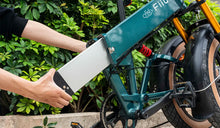 Un hombre está quitando la batería externa de una bicicleta eléctrica Fiido M1 PRO.