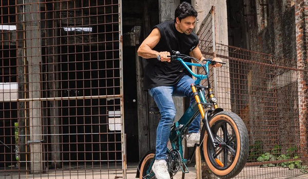 Un hombre está montando una bicicleta eléctrica de montaña Fiido M1 Pro en un sendero de montaña.
