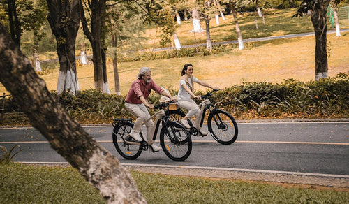 Dos ciclistas montando bicicletas eléctricas de turismo Fiido Nomads Pro por una calle de la ciudad