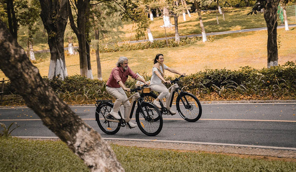 Dos ciclistas montando bicicletas eléctricas de turismo Fiido Nomads Pro por una calle de la ciudad