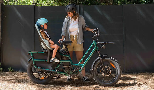 Una mujer usa una bicicleta eléctrica Fiido T2 con un asiento infantil trasero.