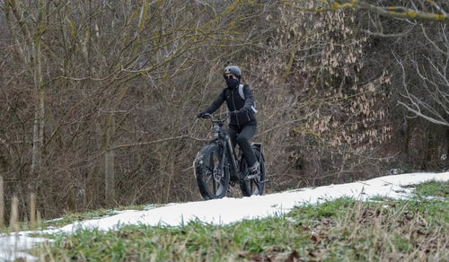 Una mujer conduce una bicicleta eléctrica Fiido Titan por la nieve.