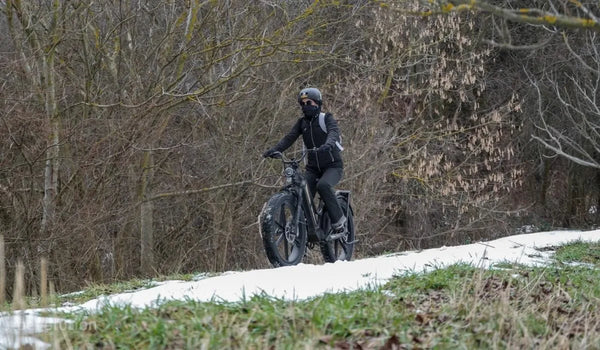 Una mujer conduce una bicicleta eléctrica Fiido Titan por la nieve.