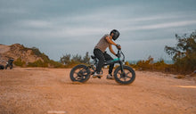 Un hombre monta una bicicleta eléctrica Fiido M1 Pro fuera de la carretera.