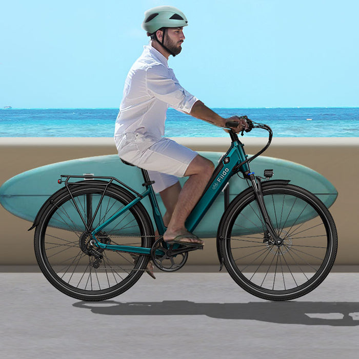 Un hombre con casco monta una bicicleta eléctrica Fiido C11 mientras sostiene una tabla de surf - m