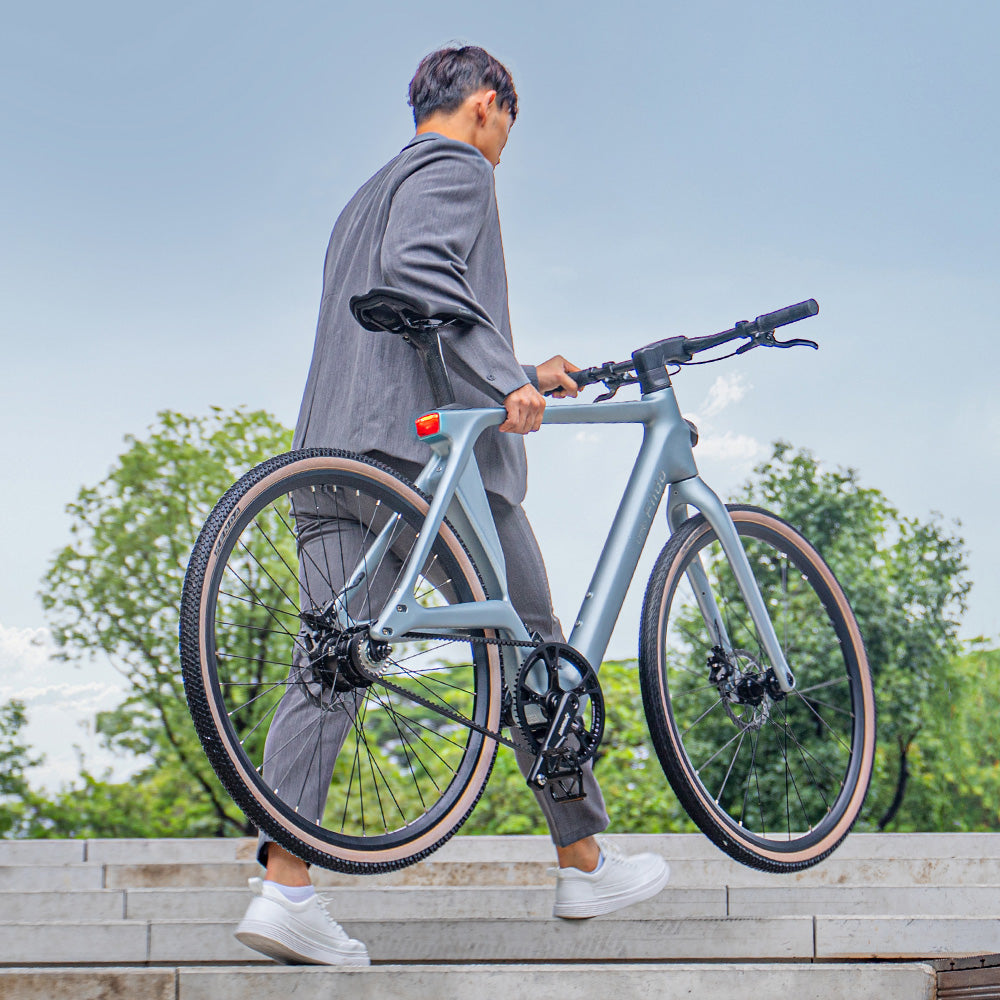 Un hombre levanta la bicicleta eléctrica Fiido Air por las escaleras